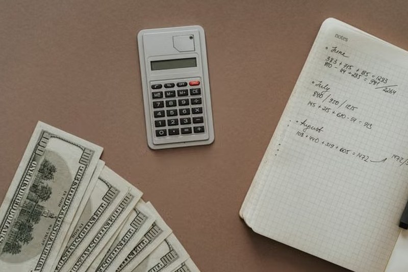 Calculator, notebook and US dollar bills on a desk